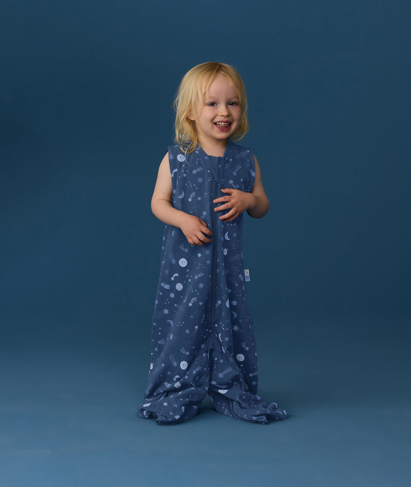 Smiling toddler wearing an ergoPouch Jersey Sleep Suit Bag 0.2 TOG Starbeam, a sleeping bag that converts to a sleep suit with legs.