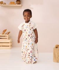 Toddler standing looking at the camera wearing ergoPouch Sleep Suit bag 1.0 TOG Bon Appetit