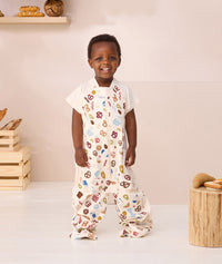 Toddler standing looking at the camera wearing ergoPouch Sleep Suit bag 1.0 TOG Bon Appetit