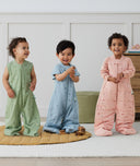Three toddlers wearing an ergoPouch sleep suit bag in different colours and prints.
