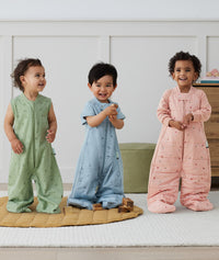 Three toddlers wearing an ergoPouch sleep suit bag in different colours and prints.