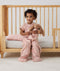 Toddler sitting on side of bed made with ergoPouch Organic Toddler Pillow And Case Daisies