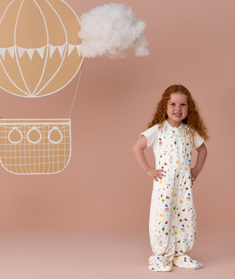 Toddler wearing an ergoPouch Sleep Suit Bag 1.0 TOG Daydream, a sleeping bag that converts to a sleep suit with legs by a four-way zipper feature. 