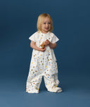 Toddler wearing an ergoPouch Sleep Suit Bag 1.0 TOG Daydream, a sleeping bag that converts to a sleep suit with legs by a four-way zipper feature. 