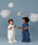 Two children wearing ergoPouch Sleep Suit Bag 1.0 TOG Daydream and Starbeam, a sleeping bag that converts to a sleep suit with legs by a four-way zipper feature. 