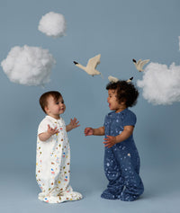 Two children wearing ergoPouch Sleep Suit Bag 1.0 TOG Daydream and Starbeam, a sleeping bag that converts to a sleep suit with legs by a four-way zipper feature. 