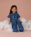 Smiling toddler sitting on a cloud, wearing an ergoPouch Sleep Suit Bag 1.0 TOG Starbeam, a sleeping bag that converts to a sleep suit with legs.
