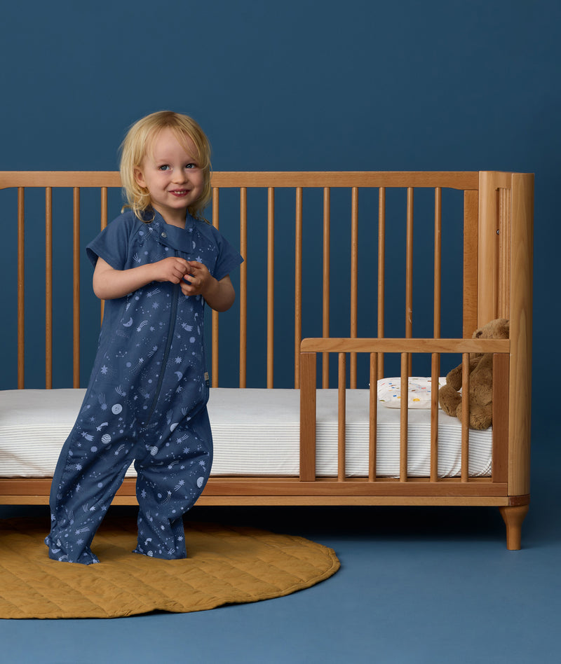 Toddler wearing an ergoPouch Sleep Suit Bag 1.0 TOG Starbeam, a sleeping bag that converts to a sleep suit with legs.