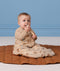 Infant sitting on a quilted mat wearing a 2.5 TOG Sleep Suit Bag in bag mode.