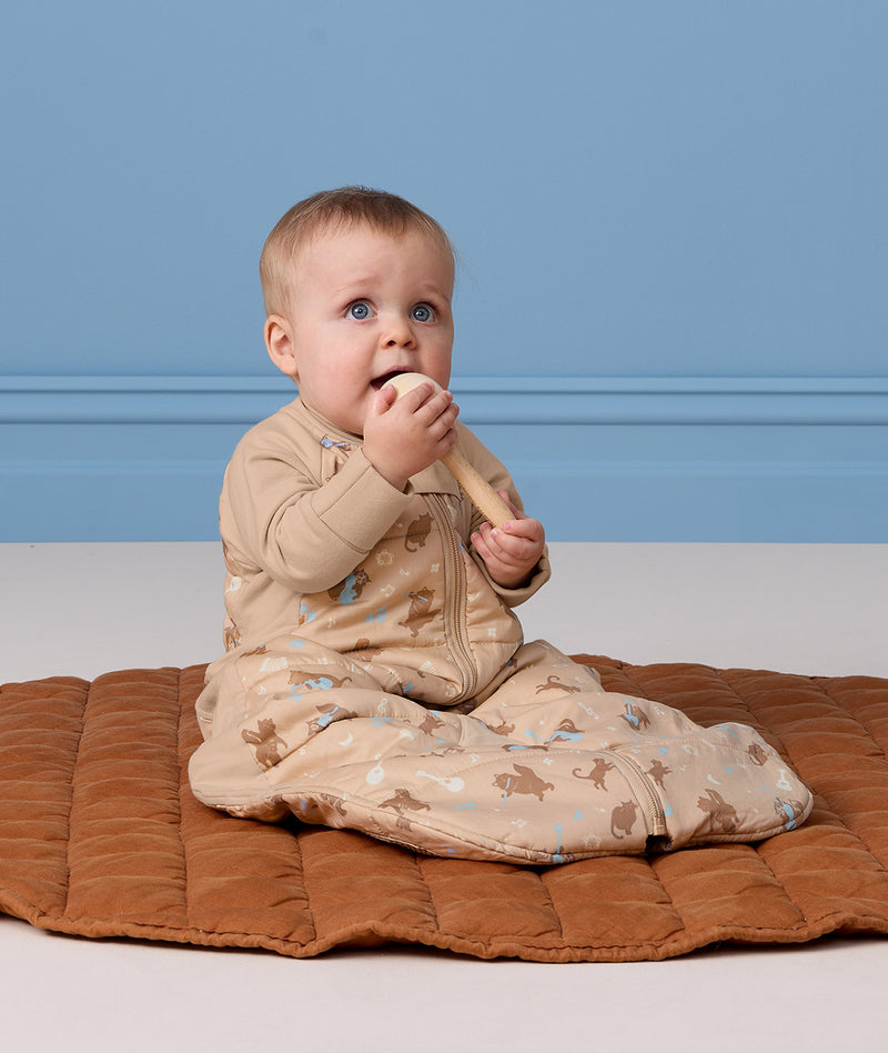 Infant sitting on a quilted mat wearing a 2.5 TOG Sleep Suit Bag in bag mode.