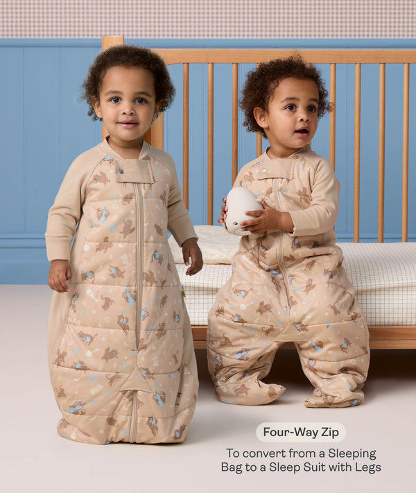 Toddler demonstrating a convertible beige Sleep Suit bag in front of a cot, with one zipped into a bag and the other split into legs. Text overlay reads: 