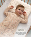 Toddler wearing a beige patterned Sleep Suit Bag, resting his head on a small matching Organic Toddler Pillow in a cot. Text on the right reads: 