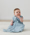 Infant sitting upright wearing a blue dragonfly-patterned sleeping bag