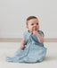 Infant sitting upright wearing a blue dragonfly-patterned sleeping bag