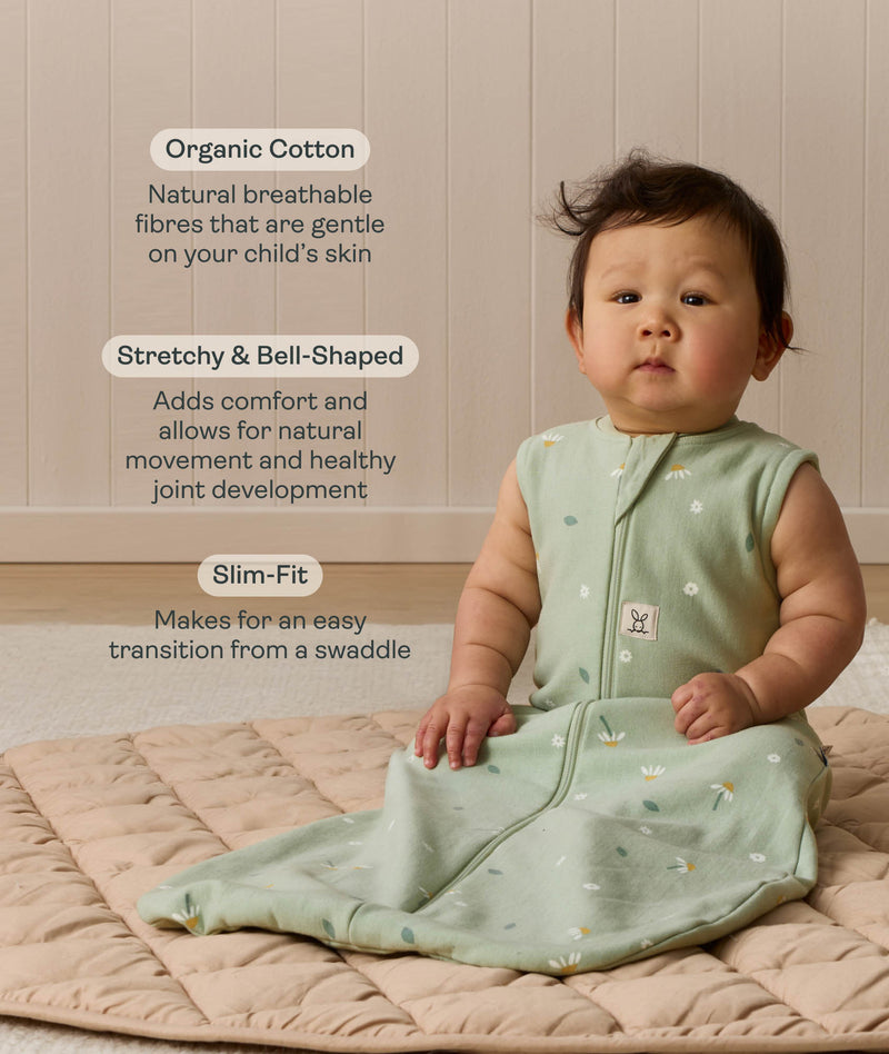 Infant sitting upright on a quilted mat, wearing a sleeveless sage green Sleeping Bag 1.0 TOG with text highlighting 