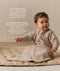 Infant wearing a long-sleeve Sleeping Bag 1.0 TOG Taupe Marle, sitting on a quilted mat with text highlighting 