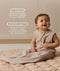 Smiling infant dressed in a sleeveless Sleeping Bag 1.0 TOG Taupe Marle, sitting on a quilted mat with text highlighting 