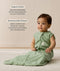 Infant wearing an ergoPouch Sleeping Bag 1.0 TOG Willow with text overlay highlighting organic cotton and stretchy & bell-shaped design.