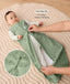 Baby lying on a padded mat while an adult adjusts the zipper of the baby's green sleeveless sleeping bag with text overlay highlighting two-way zip design for easy nappy changing and a close-up view of the dual zippers.