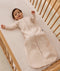 Infant dressed in a long-sleeve patterned Sleeping Bag 1.0 TOG, lying in a wooden cot