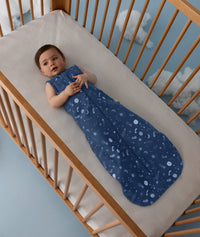 Baby lying in a crib wearing an ergoPouch Sleeping Bag 1.0 TOG Starbeam 