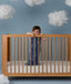 Child standing in a wooden crib wearing an ergoPouch Sleeping Bag 1.0 TOG Starbeam