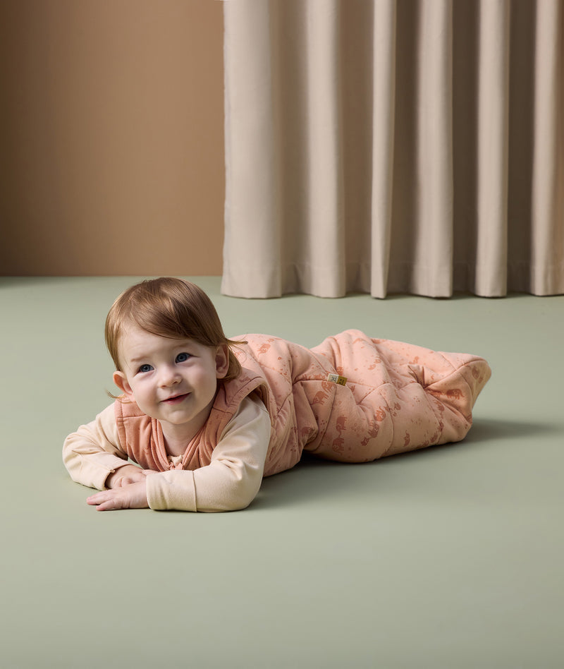Infant lying flat on its stomach, dressed in an ergoPouch 2.5 TOG Sleeping Bag with a Long Sleeve Layer underneath.