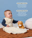 Infant wearing a cream Sleeping Bag 2.5 TOG, sitting next to a plush toy on a quilted mat with text highlighting organic cotton and stretchy bell-shaped design.