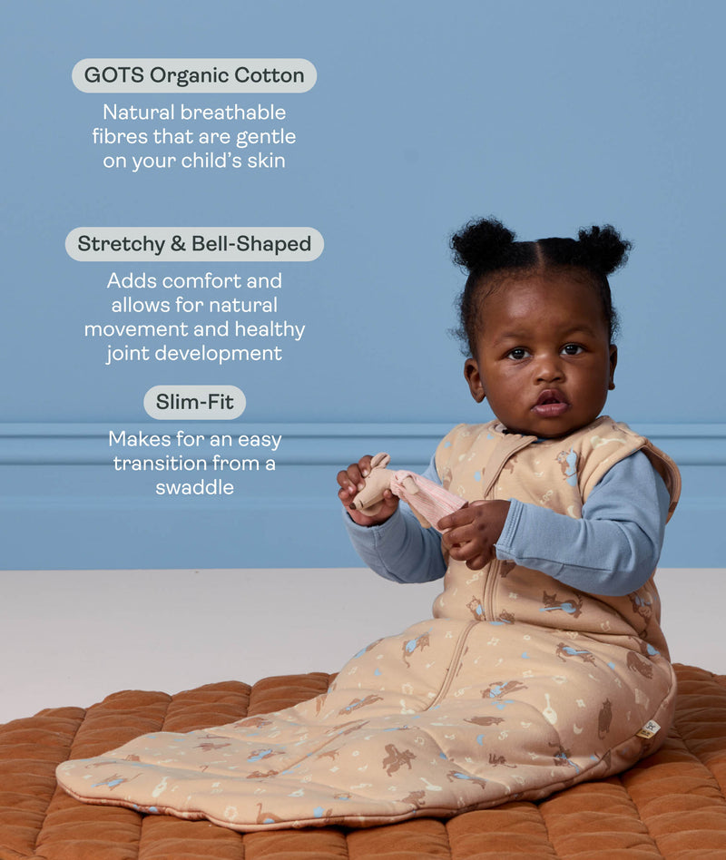 Baby sitting on a mat wearing a patterned beige Sleeping Bag with product feature callouts for GOTS organic cotton, stretchy bell shape, and slim fit features.