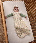 Baby lying in a cot, wearing an ergoPouch 2.5 TOG Sleeping Bag with a Long Sleeve Layer underneath.