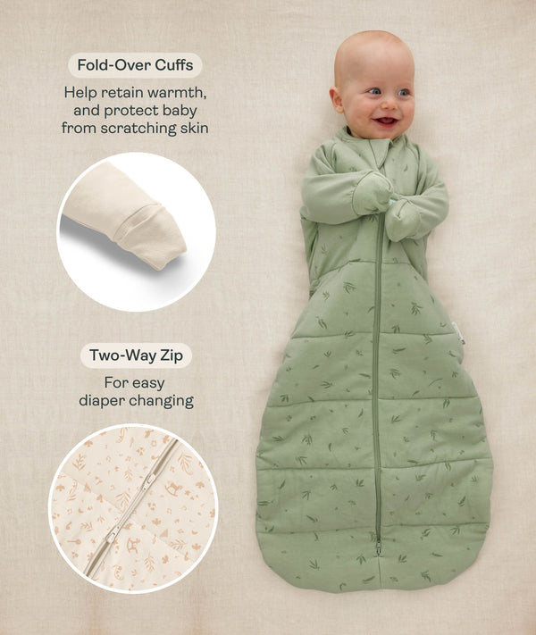 Baby lying down in a sage green Sleeping Bag 3.5 TOG, with inset images and text highlighting fold-over cuffs and a two-way zipper.