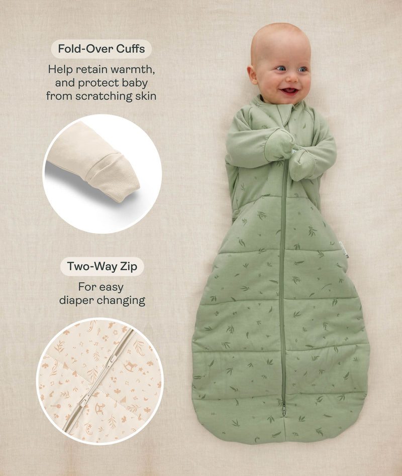 Baby lying down in a sage green Sleeping Bag 3.5 TOG, with inset images and text highlighting fold-over cuffs and a two-way zipper.