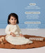 Infant sitting on a mat playing with a toy while wearing a cream patterned long-sleeve Sleeping Bag, with text highlighting its slim-fit, GOTS organic cotton, and stretchy bell-shaped design.