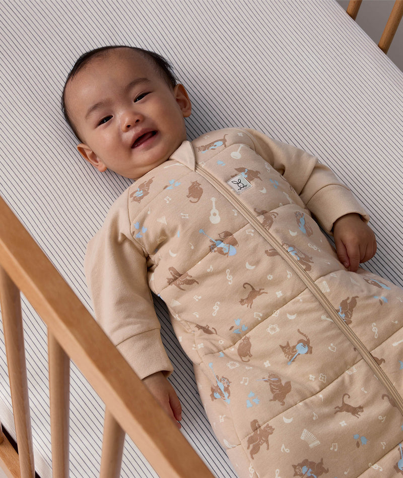 Baby lying in a cot wearing a printed Sleeping Bag 3.5 TOG Sleeved Melody