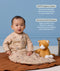 Baby sitting next to a stuffed animal while wearing a printed beige long-sleeve Sleeping Bag, with text highlighting GOTS organic cotton and stretchy bell-shaped design.
