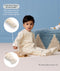 Toddler sitting on the floor playing a wooden xylophone in a cream patterned Sleep Onesie, with callouts demonstrating fold-over hand and foot cuffs for warmth and scratch protection.