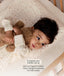 Toddler lying on a printed pillow hugging a stuffed teddy bear, with promotional text overlay reading 