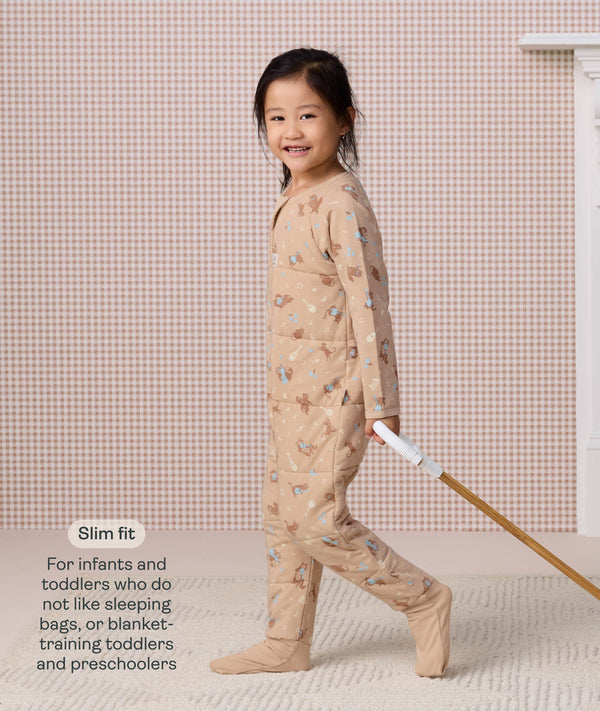 Preschooler walking while pulling a wooden toy, wearing a slim-fit beige patterned Sleep Onesie, with text describing its design for toddlers and preschoolers.
