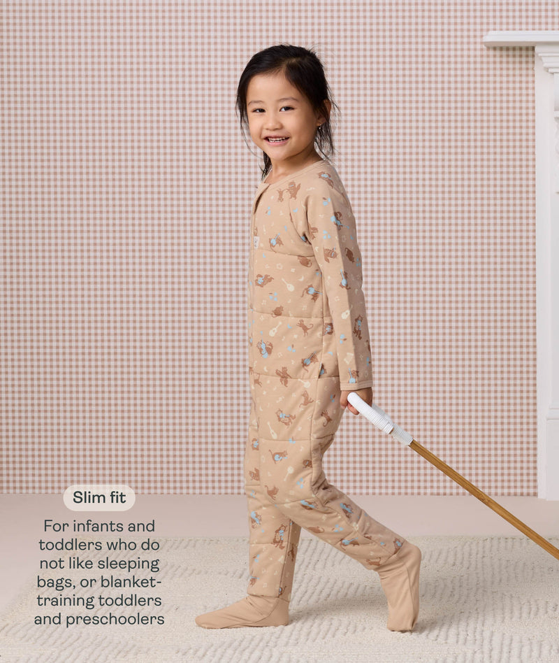 Preschooler walking while pulling a wooden toy, wearing a slim-fit beige patterned Sleep Onesie, with text describing its design for toddlers and preschoolers.