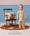 Toddler wearing a beige patterned Sleep Onesie standing next to a wooden rocking chair with a teddy bear, with text highlighting an Organic Toddler Pillow.