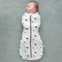 A sleeping baby wearing a Cocoon Swaddle Bag 1.0 TOG Clouds