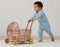 Toddler wearing a blue ergoPouch sleep onesie, pushing a wicker toy.