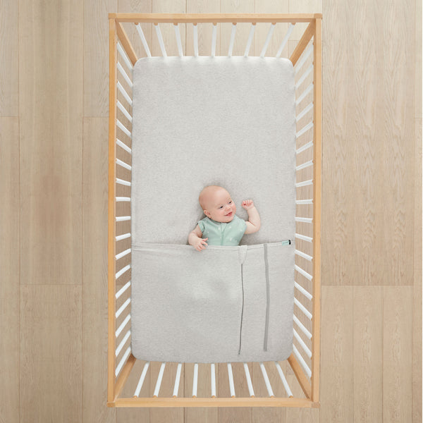 Baby lying in cot under ergoPouch HugMe Blanket 0.2 & 1.0 TOG in Grey Marle 