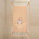 Baby lying in cot wearing ergoPouch HugMe Blanket 0.2 & 1.0 TOG in Wheat 