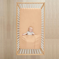 Baby lying in cot wearing ergoPouch HugMe Blanket 0.2 & 1.0 TOG in Wheat 