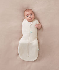 Newborn wearing an ergoPouch Cocoon Swaddle Bag 1.0 TOG Oatmeal Marle with one arm out