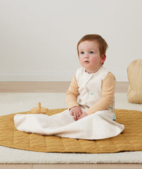 Baby with hip dysplasia siting up wearing ergoPouch Hip Harness Jersey Sleep Bag 0.2 TOG Oatmeal Marle