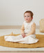 Baby with hip dysplasia siting up wearing ergoPouch Hip Harness Jersey Sleep Bag 0.2 TOG Oatmeal Marle