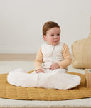 Newborn sitting, wearing an ergoPouch Hip Harness Jersey Sleeping Bag 2.5 TOG Oatmeal Marle