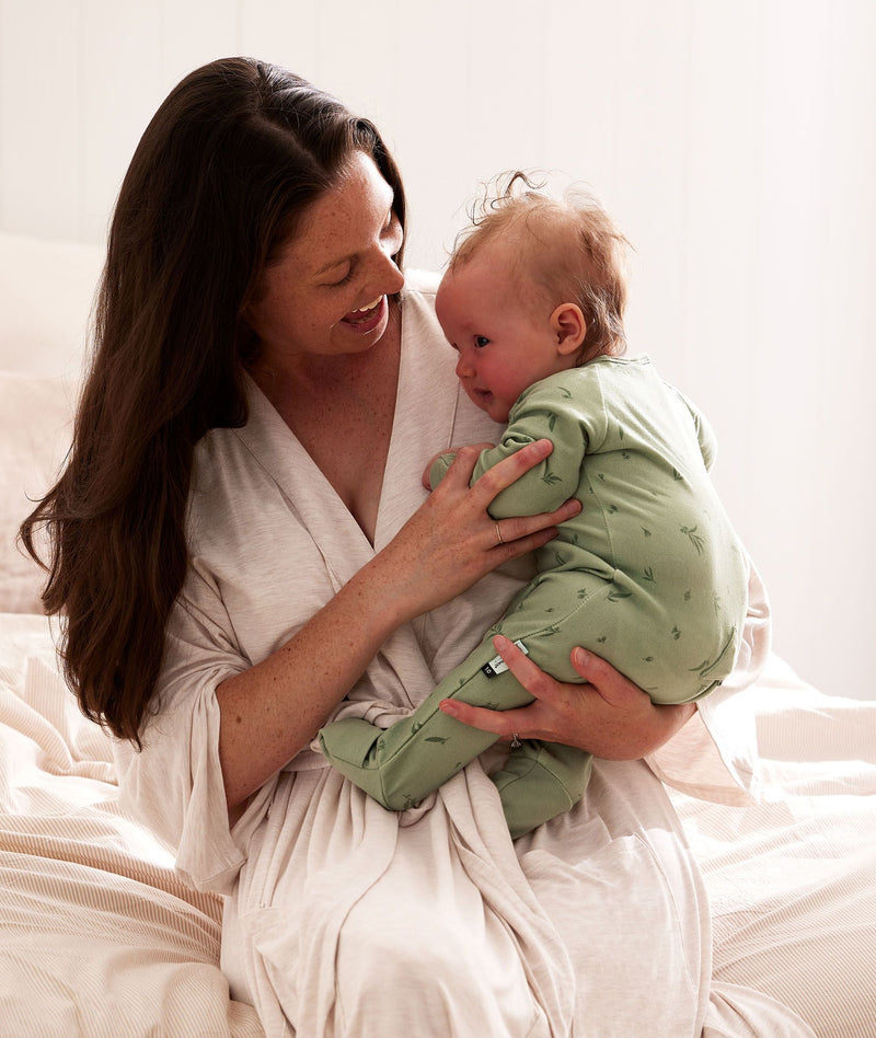 Mum wearing a an ergoPouch Matchy Matchy Robe Oatmeal Marle, holding a child